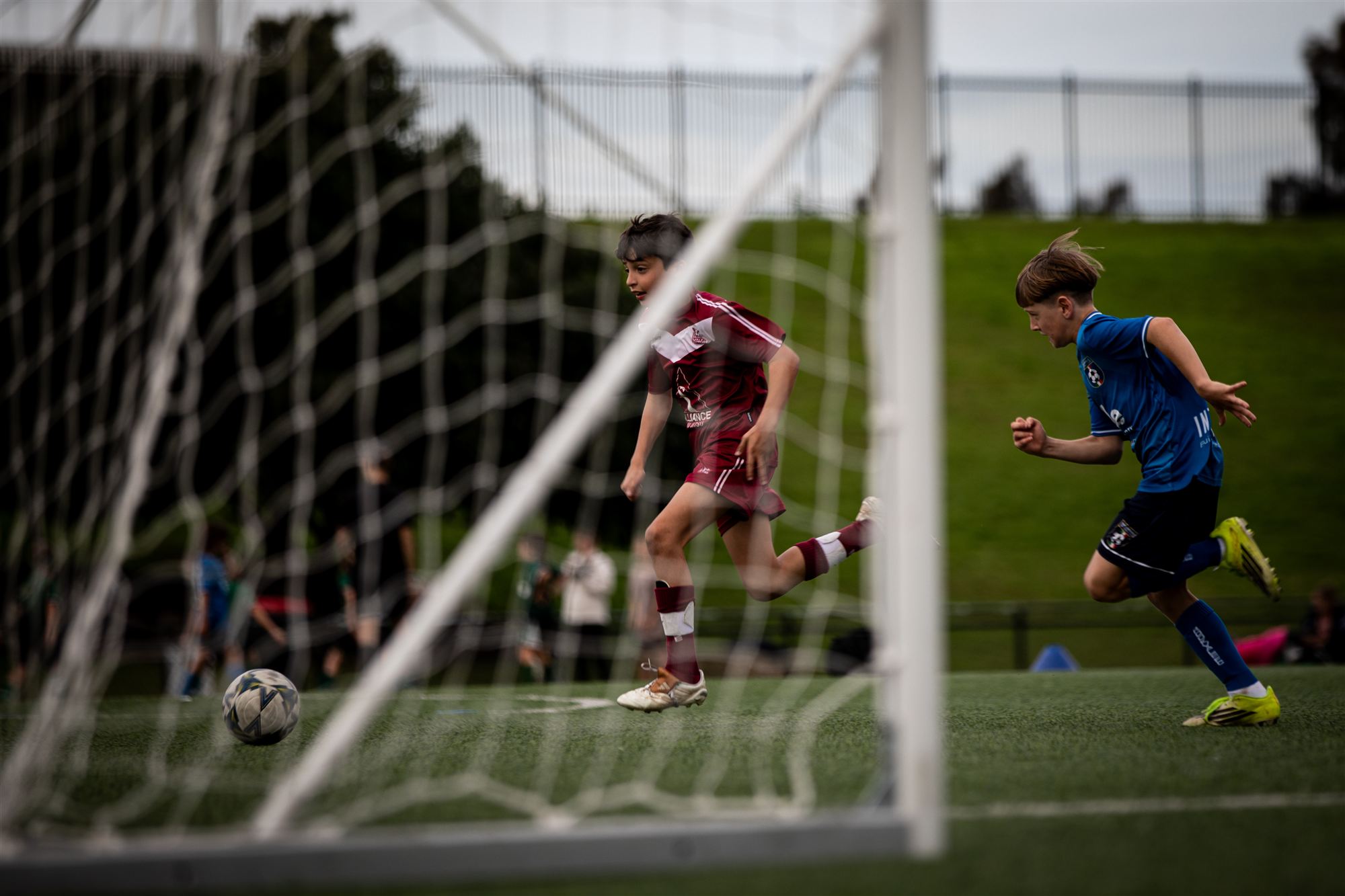 Players framed through the goal netting mid-run